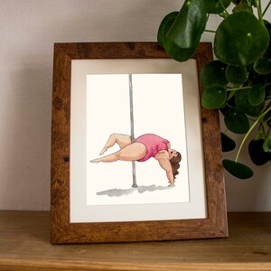 May include: A framed illustration of a person in a pink leotard performing a pole dance move. The person is facing away from the viewer and is holding onto a silver pole with their left hand. The person's right leg is extended out to the side, and their left leg is bent at the knee. The person's hair is brown and is pulled back into a ponytail.