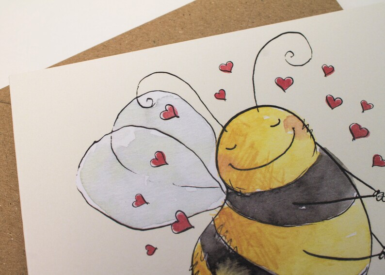 Op de afbeelding: Een aquarel schilderij van een cartoon bij met gesloten ogen en een glimlach. De bij heeft zwart-gele strepen en witte vleugels. De bij is omringd door kleine rode hartjes.