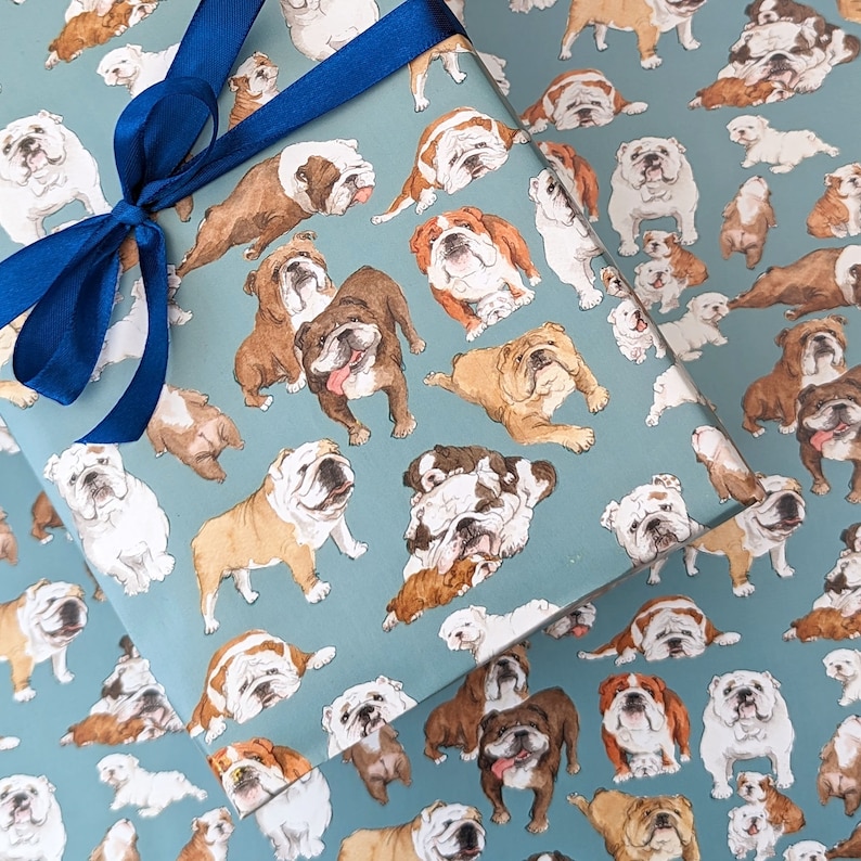 May include: Blue and white wrapping paper with a repeating pattern of bulldog illustrations. The bulldogs are in various poses and sizes, and some are wearing collars.