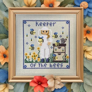 Könnte beinhalten: Ein Kreuzstich-Stickmuster mit einer Frau in einem weißen Imkeranzug mit dem Text "Keeper of the Bees". Das Design enthält Bienen, Blumen und einen Bienenstock.