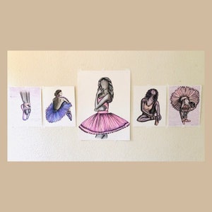May include: Five watercolor illustrations of ballerinas in various poses. The drawings feature pink and purple tutus, pointe shoes, and detailed depictions of the dancers' forms. The artwork is displayed on a neutral wall.
