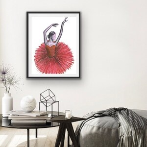 Könnte beinhalten: Eine gerahmte Illustration einer Ballerina, die ein rotes Tutu trägt und eine Tanzpose einnimmt. Die Ballerina ist in Schwarzweiß gezeichnet, während das Tutu ein leuchtendes Rot ist.
