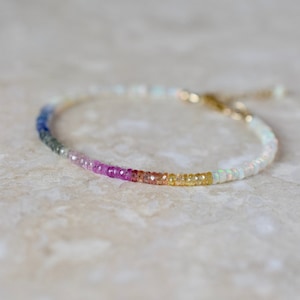 A dainty beaded gemstone bracelet designed with colourful Ethiopian Opals and featuring a central segment of an array of coloured sapphire rondelles.