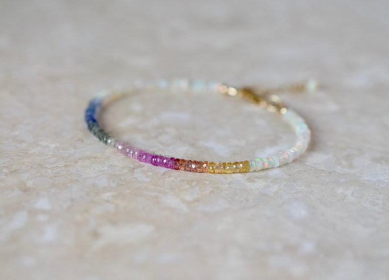 A dainty beaded gemstone bracelet designed with colourful Ethiopian Opals and featuring a central segment of an array of coloured sapphire rondelles.