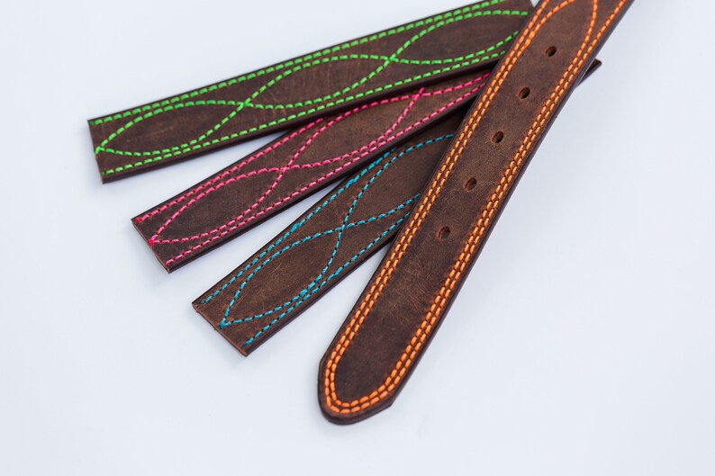 May include: Four dark brown leather straps featuring decorative stitching in vibrant neon colors. Three straps display a repeating crisscross pattern in lime green, hot pink, and bright blue, while the fourth strap has orange edge stitching.