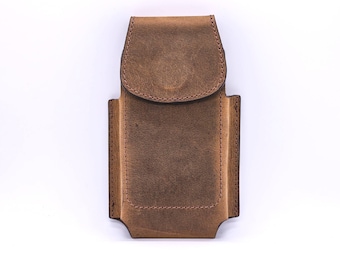 May include: A brown leather belt pouch featuring a rectangular body with a rounded flap closure. The accessory has visible stitching along the edges and a structured design, providing a secure storage space for small personal items or tools.