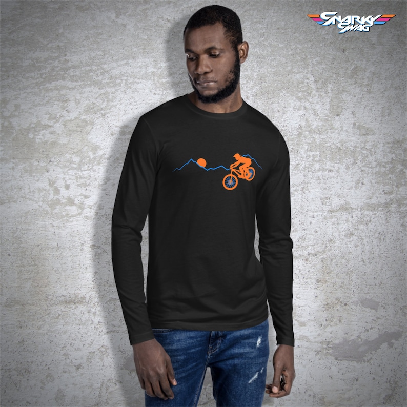 May include: A black long-sleeve t-shirt with an orange silhouette of a person riding a bicycle over a blue mountain range with an orange sun in the background.