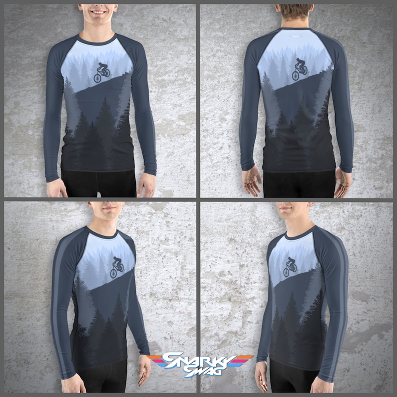 May include: A long-sleeved shirt with a blue and white color scheme. The shirt features a graphic of a person riding a mountain bike down a hill with trees in the background. The shirt has a raglan sleeve design with a contrasting color stripe on the sleeves.