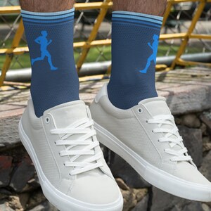 May include: A pair of blue athletic socks with a white stripe and a blue running figure design. The socks are worn with white sneakers.