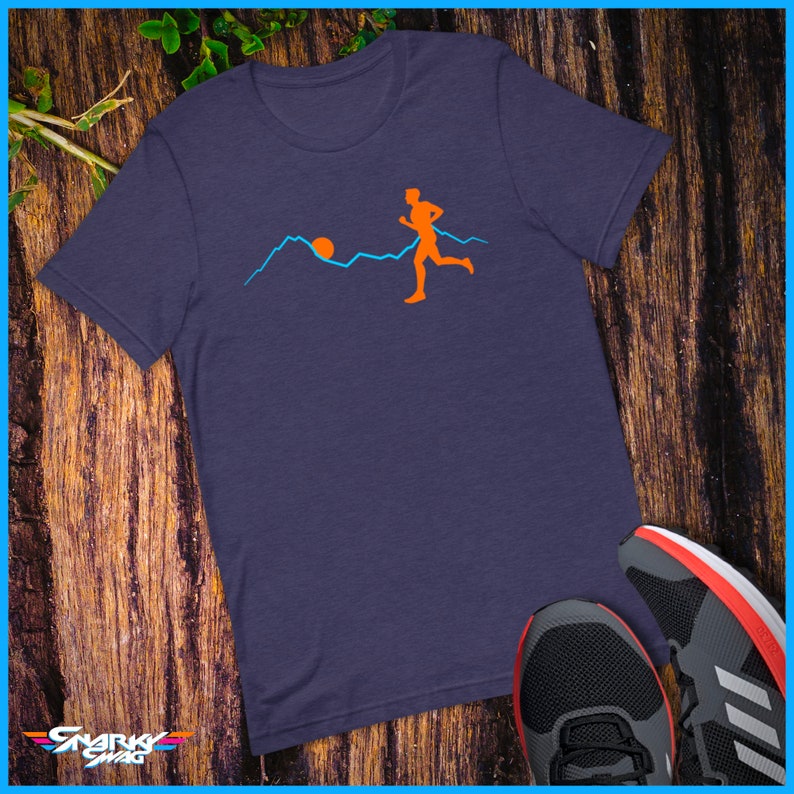 May include: A navy blue t-shirt featuring a graphic of a person running in front of a mountain range with a setting sun.