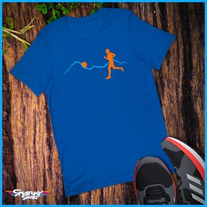 May include: A royal blue t-shirt featuring a graphic of a person running across a mountain range with a sun rising in the background.