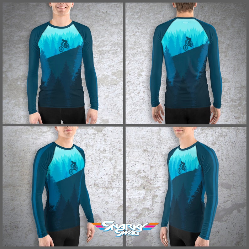 May include: A blue long-sleeve shirt with a graphic of a mountain biker riding through a forest. The shirt has a white stripe on the sleeves and a white crew neck.