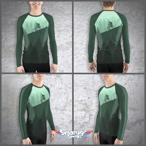 May include: A green long-sleeve shirt with a mountain biking design. The shirt has a white and green color scheme and features a silhouette of a mountain biker riding down a hill.