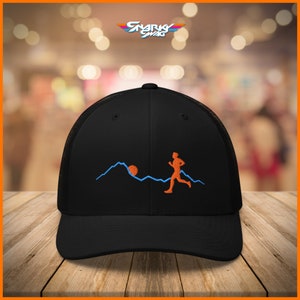 Puede incluir: Gorra de camionero negra con un dise&ntilde;o bordado en azul y naranja de una persona corriendo sobre una cordillera con un sol.