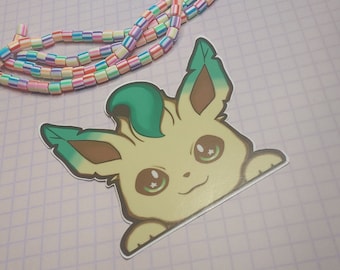 May include: A sticker of a cartoon Eevee with green and brown ears, yellow fur, and big brown eyes with a star in each eye. The Eevee is peeking out from behind a white border.