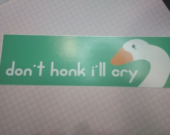 May include: A green and white sticker with a cartoon goose with a tear on its face. The sticker says "don't honk I'll cry".