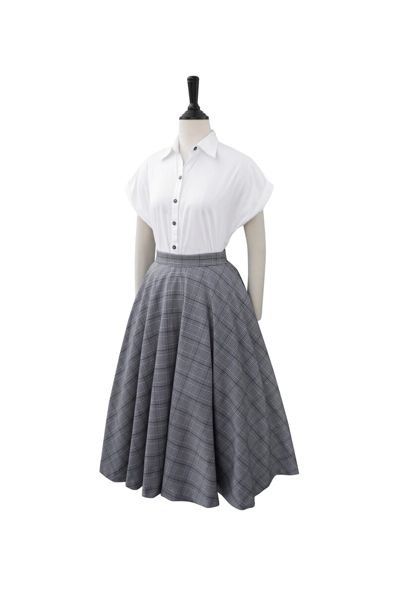 May include: A white button-down shirt with short sleeves and a gray and white plaid skirt.