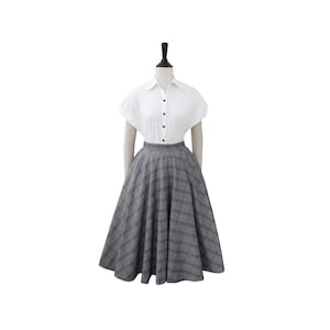 May include: A gray and black plaid skirt with a full, A-line silhouette. The skirt is knee-length and has a high waist.
