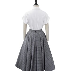 May include: A white short-sleeved shirt with a gray and white plaid skirt. The skirt is full and has a high waist.