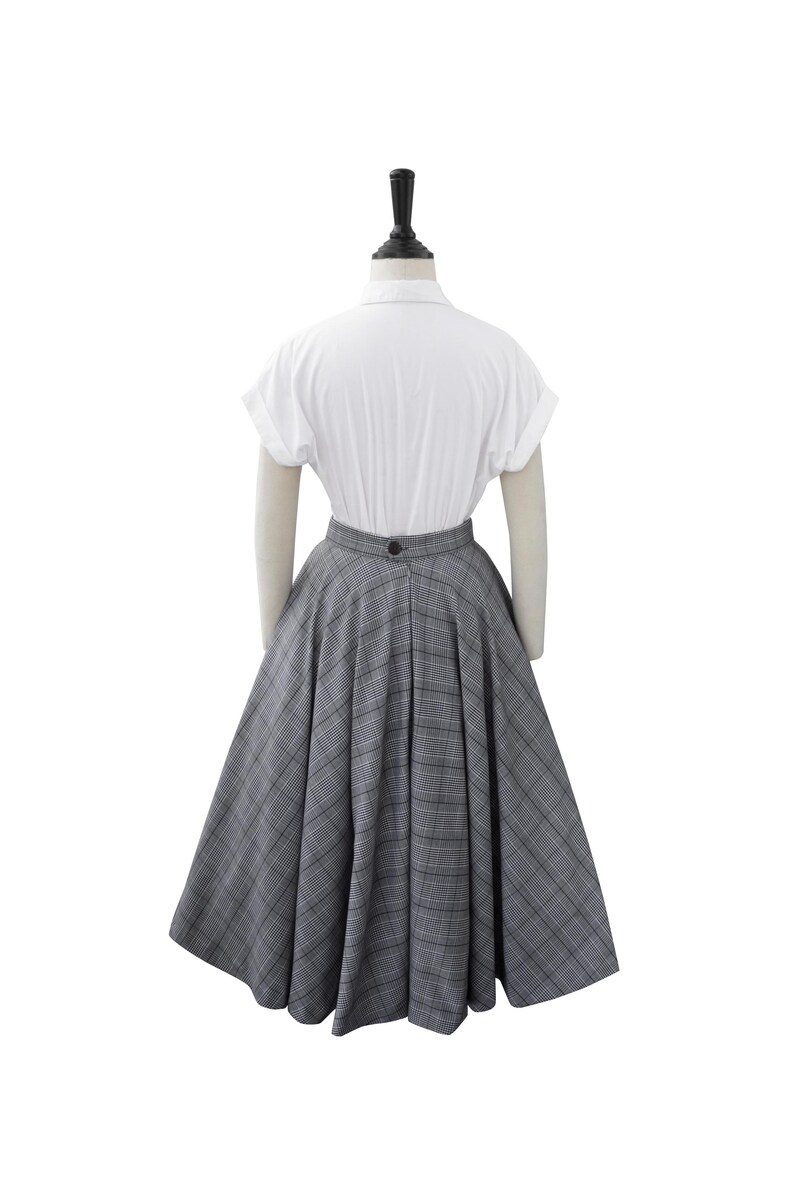 May include: A white short-sleeved shirt with a gray and white plaid skirt. The skirt is full and has a high waist.