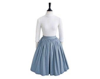 May include: A light blue full skirt with a gathered waistline. The skirt is made of a soft, flowing fabric and has a simple, elegant design.