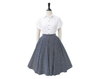 May include: A white short-sleeved button-down shirt paired with a navy blue polka dot skirt. The skirt is a full, flared style. The outfit is displayed on a mannequin against a white background.
