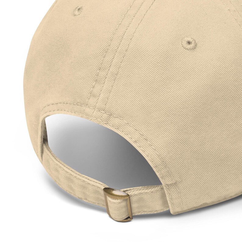 Pode incluir: Bon&eacute; de beisebol bege com aba curva e al&ccedil;a ajust&aacute;vel. O bon&eacute; apresenta um fecho de fivela de metal e um design costurado. A parte de tr&aacute;s do bon&eacute; &eacute; vis&iacute;vel, mostrando a al&ccedil;a ajust&aacute;vel e a constru&ccedil;&atilde;o.
