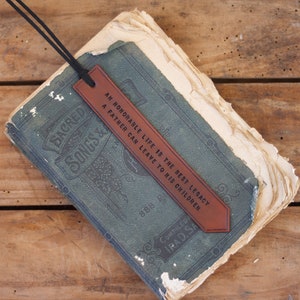 May include: A brown leather bookmark with the text "An honourable life is the best legacy a father can leave to his children" on a vintage book.