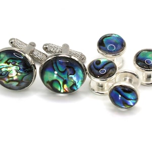 May include: A set of six cufflinks and studs featuring iridescent abalone shell in shades of blue, green, and gold. The cufflinks and studs are silver-toned.