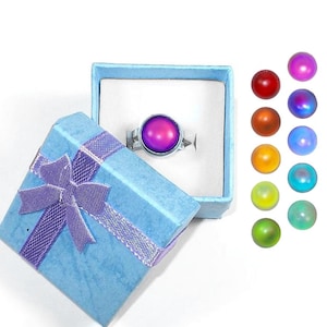 May include: A silver-toned mood ring with a large, round, color-changing stone is displayed in a light blue gift box with a purple ribbon. Several color samples are shown to the right of the ring.