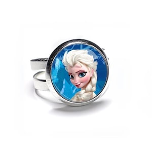 May include: A silver-toned adjustable ring featuring a circular image of Elsa from the movie Frozen. Elsa has blonde hair and is set against a blue background. The ring is a fun accessory for fans of the animated film.