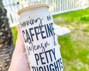 May include: White tumbler with a black and white design that says "running on caffeine, sarcasm & petty thoughts". The tumbler has a bamboo lid and a clear straw.