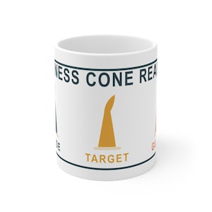 May include: A white ceramic mug featuring a graphic design with dark blue horizontal lines at the top and bottom. The text reads NESS CONE REA, with a yellow cone icon labeled TARGET in yellow text, and partial text reading DE and GU.