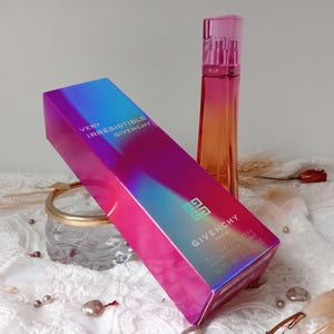 May include: A perfume set featuring a box and bottle. The box has a blue, pink, and purple gradient with "Very Irrésistible Givenchy" and the Givenchy logo. The bottle is tall, slender, with a pink cap and an orange to pink gradient.