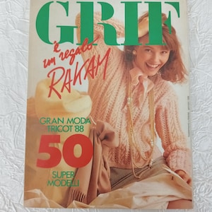 May include: A vintage magazine cover with the word "GRIF" in large green letters. The cover features a smiling woman wearing a pink knitted sweater and a long gold necklace. The text "RAKAM" and "50 SUPER MODELLI" are also visible.