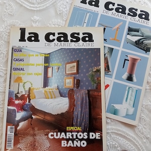 Peut inclure: Deux numéros vintage du magazine La Casa de Marie Claire. Le magazine au premier plan montre un intérieur de chambre avec un lit en bois, du papier peint bleu et le texte La Casa de Marie Claire, Abril 1994, et Especial Cuartos de Baño. L'autre montre des meubles.