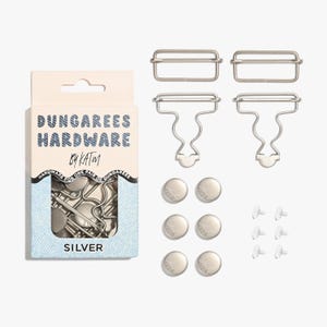 May include: A set of silver-colored dungarees hardware components, including buckles, clips, buttons, and screws. The hardware is packaged in a small box with the text "DUNGAREES HARDWARE by KAT M" and the word "SILVER".