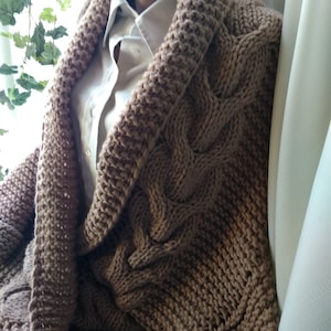 May include: A brown knitted cardigan with a large collar and cable knit pattern.