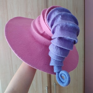 May include: A pink and purple felt hat with a curled brim and a long, curled purple felt horn.