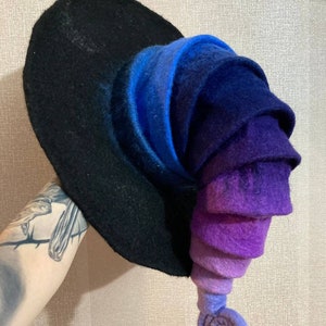 May include: A purple and blue gradient witch hat with a curled brim and a pointed top. The hat is made of felt and has a black base.