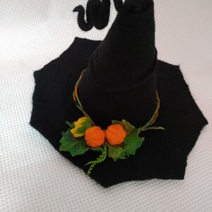 May include: A black felt witch hat with a curled brim and two orange felt pumpkins attached to the front.