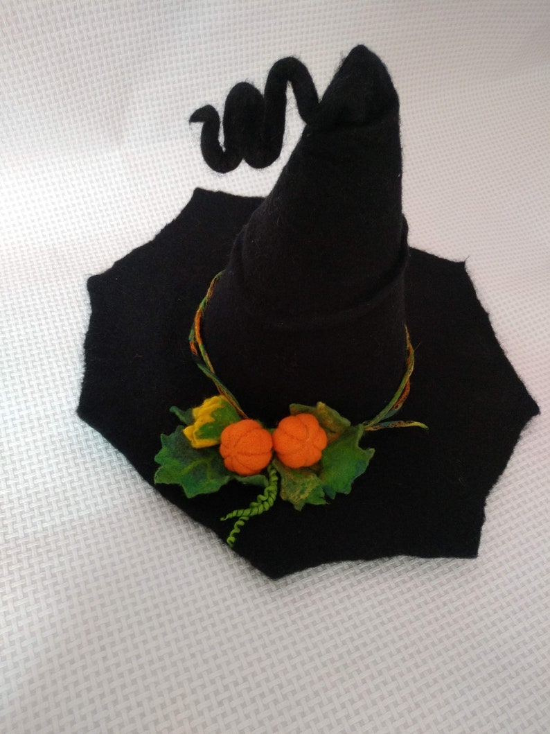May include: A black felt witch hat with a curled brim and two orange felt pumpkins attached to the front.