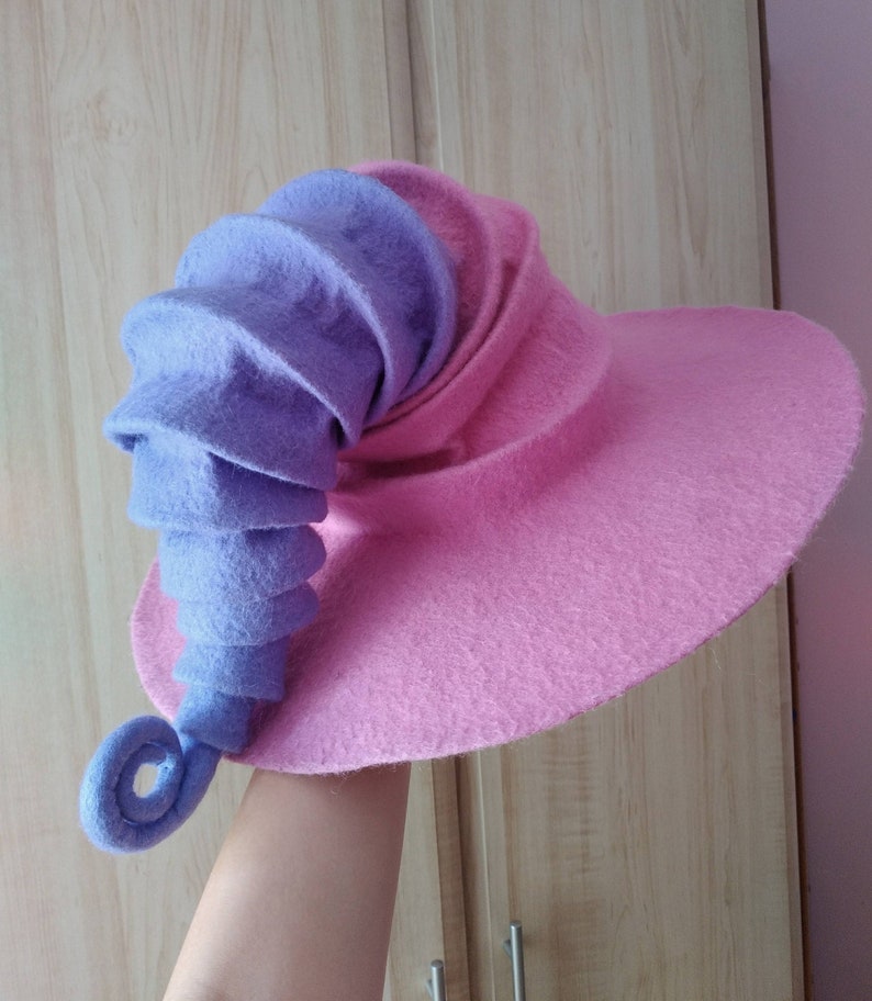 May include: A pink and purple felt witch hat with a curled brim and a long, curled purple felt brim.