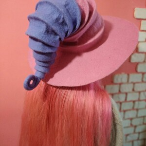May include: A pink and purple felt witch hat with a curled brim and a tall, curled purple felt horn.