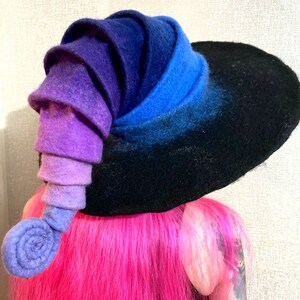 May include: A black felt witch hat with a large brim and a purple, blue, and black gradient spiral on the side.