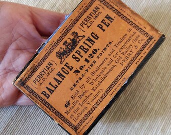 Könnte beinhalten: Eine Vintage-Box für einen Perryian Balance Spring Pen, Nr. 120, mit extra feinen Spitzen. Die Box ist orange mit schwarzem Text und einem dekorativen Rand. Der Text lautet "Verkauft von allen Schreibwarenhändlern und Händlern von Metallfedern. Großhandel und für den Export im Londoner Geschäft, Old Bailey (früher Holborn Viaduct). Perry & Co."
