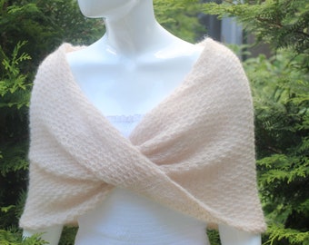 May include: A soft, pale pink knitted shawl with a delicate texture. The shawl is draped over a mannequin's shoulders and is styled in a criss-cross pattern.