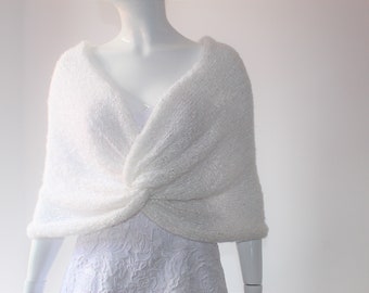 May include: White knitted shawl with a knotted design. The shawl is draped over a white dress.
