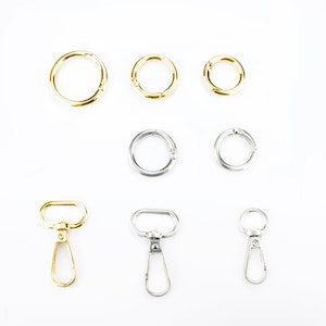 May include: Assortment of gold and silver key rings and swivel clasps. The key rings are round and come in different sizes. The swivel clasps are made of metal and have a hook on one end.