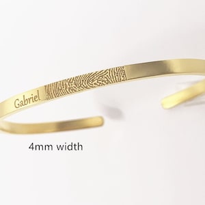 Puede incluir: Pulsera de oro con un diseño de huella digital y el nombre "Gabriel" grabado. La pulsera tiene 4 mm de ancho.